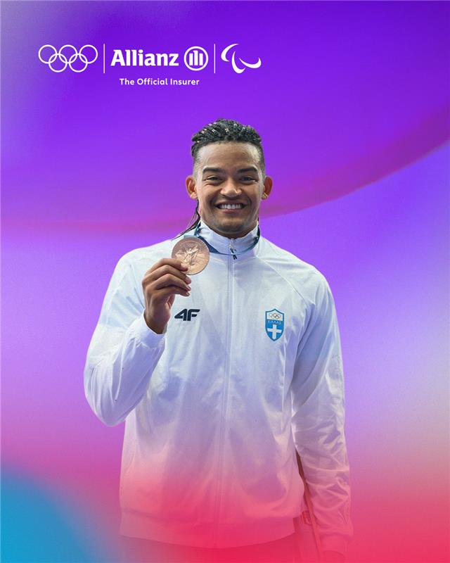 Manolo Karalis holding a gold medal in Allianz background.